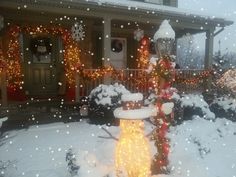 a snowman in front of a house decorated for christmas