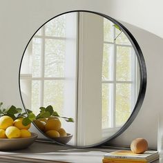 a mirror sitting on top of a table next to a bowl of lemons