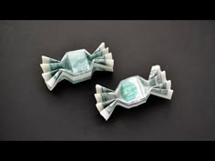 two origami fish made out of money on a black surface with one dollar bill in the center