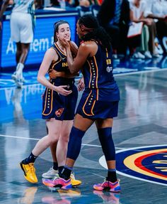 two female basketball players hugging each other on the court