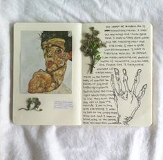 an open book with drawings on it and a hand holding a plant in the middle