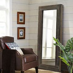 a living room with a chair, mirror and potted plant