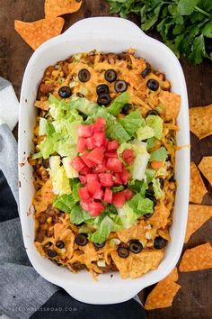 a white casserole dish filled with taco salad and tortilla chips