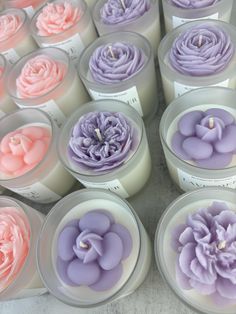 there are many candles with flowers in them on the table and one candle has pink, purple, and white frosting