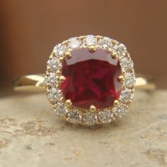 a close up of a ring with a red stone in the middle and white diamonds around it