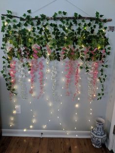 the wall is decorated with vines and lights in pink, green and white flowers on it