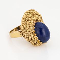 This is part of Chairish’s Fine Jewelry assortment.  Stylish lapis lazuli cocktail ring crafted in 18 karat yellow gold (circa 1960s to 1970s).   Cabochon cut lapis lazuli measures 13mm x 10mm. The lapis is in very good condition and free of cracks or chips.   Rich cobalt blue Lapis lazuli is perched on a beautifully detailed woven mount, in an almost halo like design that is so visually appealing. The butteryness of the 18k gold setting and contrasting rich cobalt blue lapis makes a bold statement on the hand. The medium rise ring (12mm - 0.47inches) sits comfortably on the finger.   The ring is in very good condition and was lightly cleaned and polished.   Particulars:  Weight: 8.6 grams  Stones:  Cabochon cut lapis lazuli measures 13mm x 10mm. The lapis is in very good condition and fre Yellow Gold Cocktail Ring, Vintage Cocktail Ring, Lapis Ring, Lapis Lazuli Ring, Gold Cocktail Ring, Jewels Rings, Gold Cocktail, Ring Crafts, Modern Ring