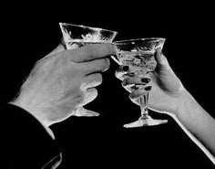 black and white photograph of two people toasting with wine glasses in front of them