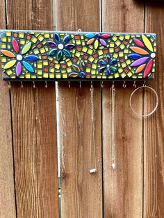 a colorful piece of art hanging on a wooden fence