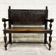 an old wooden bench sitting in front of a white brick wall with carvings on it