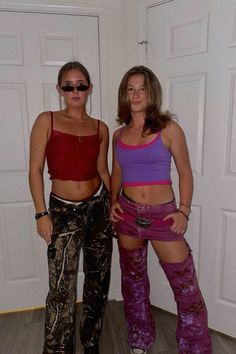 two women standing next to each other in front of a white door wearing purple and red clothing