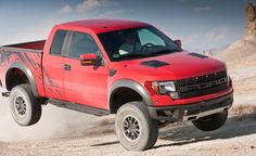 a red pick up truck driving down a dirt road