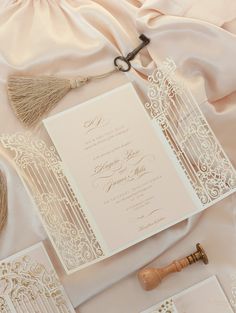 the wedding stationery is laid out on top of the white satin and has a tassel