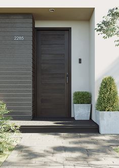 two planters are sitting in front of the entrance to a house that is painted black and white