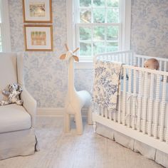 a baby's room with a white crib and blue floral wallpaper on the walls