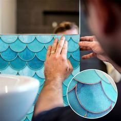 a man is working on an art project with blue tiles and gold trimmings