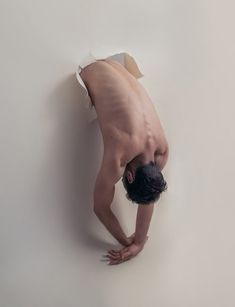 a man is upside down on the floor with his head in the wall and hands behind him