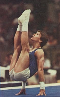 a man doing a handstand on top of a blue floor