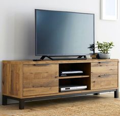 a flat screen tv sitting on top of a wooden entertainment center next to a plant