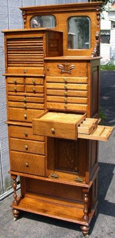 an old wooden dresser with drawers and mirror on the top, in front of a building