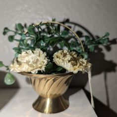 some white flowers in a gold vase on a table