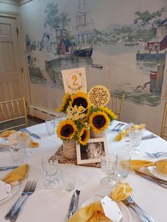 the table is set with sunflowers and place settings