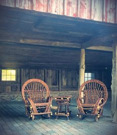 two wicker chairs sitting next to each other on top of a wooden floor in front of a building