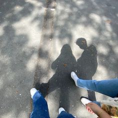 two people standing next to each other with their shadows on the ground in front of them