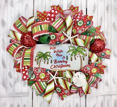 a red and green christmas wreath with palm trees on the front, which says wish you a beachy christmas