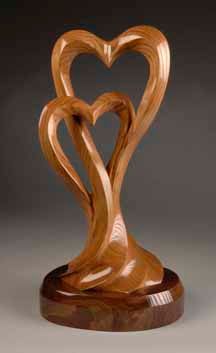 a wooden sculpture with two hearts carved into it's sides on a wood base