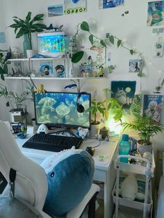 a desk with a computer, chair and plants on it