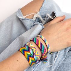 a woman wearing three different colored bracelets on her wrist and one with a knot