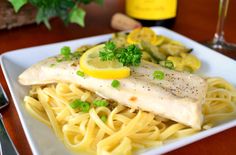 a white plate topped with pasta and fish