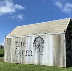 an old building with the word the farm painted on it's side in front of a grassy field