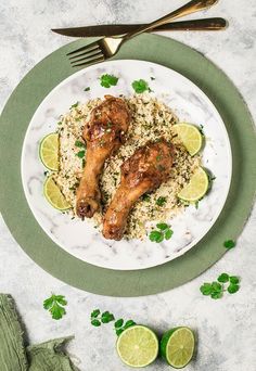 two chicken legs with rice and limes on a plate