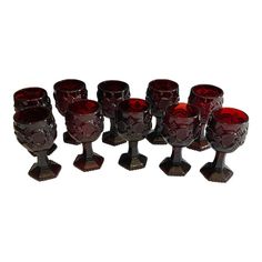 seven red glass goblets sitting next to each other