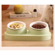 a cat sitting on the floor next to two bowls with food in front of it