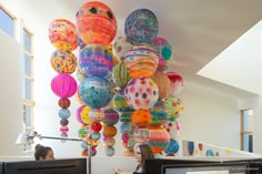 two women sitting at desks in an office decorated with colorful paper lanterns hanging from the ceiling