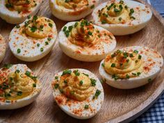 deviled eggs with mustard and chives on a wooden platter, ready to be eaten