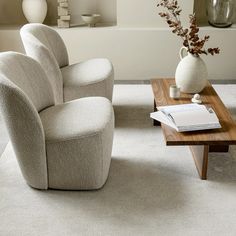 a living room filled with furniture and a vase on top of a wooden coffee table