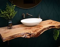 a wooden table with a white bowl on it next to a mirror and vase filled with flowers