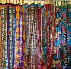 many different colored ties are hanging on a rack in front of a window with curtains