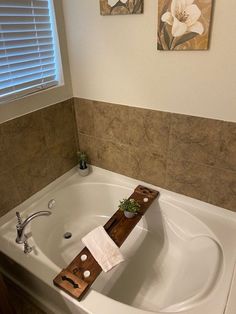 a bathroom with a large white bathtub next to a window and pictures on the wall