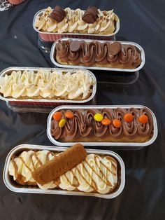 four tins filled with different types of desserts on a black tableclothed surface