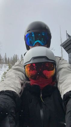 a person wearing goggles and skis in the snow with their arms around each other