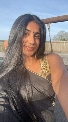 a woman with long black hair is posing for the camera while wearing a sari