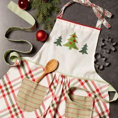 an apron with christmas tree applique on it next to other kitchen accessories and decorations