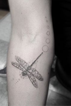 a dragonfly tattoo on the left arm and leg, with phases in the background