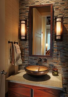 a bathroom sink sitting under a mirror in front of a wall mounted faucet