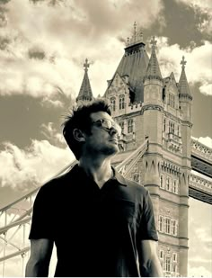 a man standing in front of a tall tower with a clock on it's side